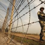 An Indian BSF soldier patrols near the fenced border with Pakistan in Suchetgarh